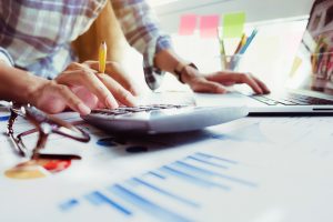 Image of Businessman hand holding pencil and financing, calculating with calculator and laptop computer on office desk, Business Accountant concept.
